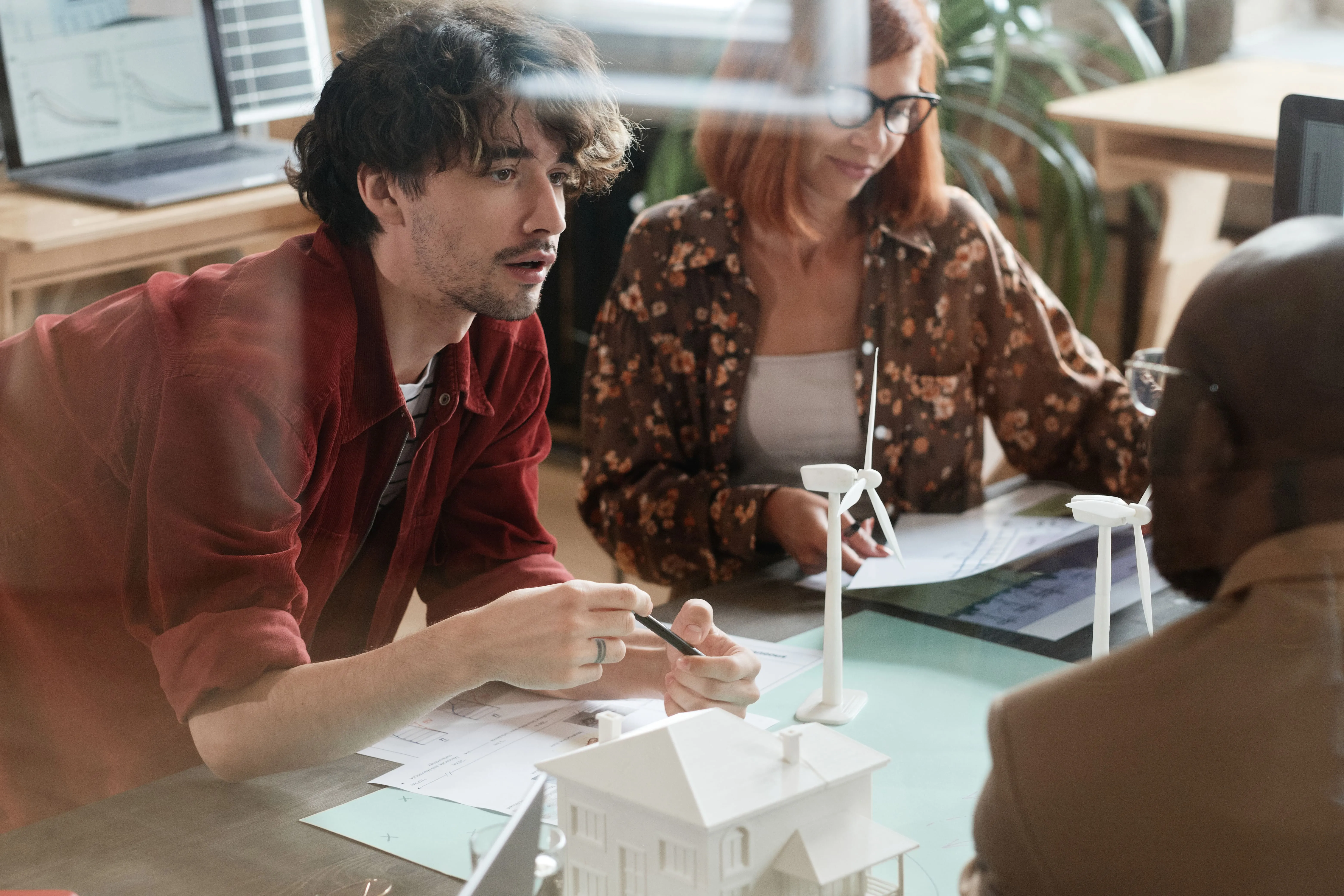 People at table with house and wind turbine models, plans